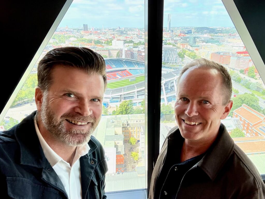 Jacob Bergström och en deltagare framför fönstret med utsikt över Göteborg och Ullevi.